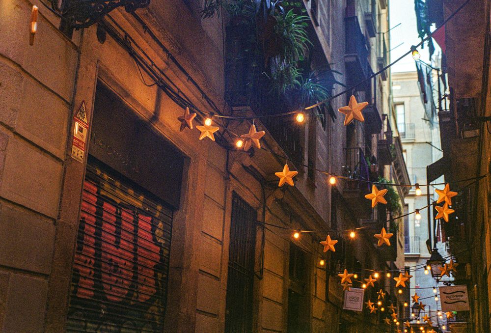Enge Altstadtgasse in Barcelona, über der Lichterketten mit großen leuchtenden Sternen gespannt sind