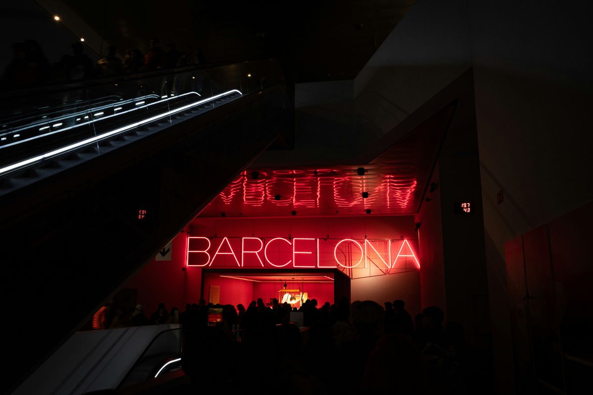 Roter Neon-Schriftzug BARCELONA über Rolltreppen in einem dunklen Innenraum