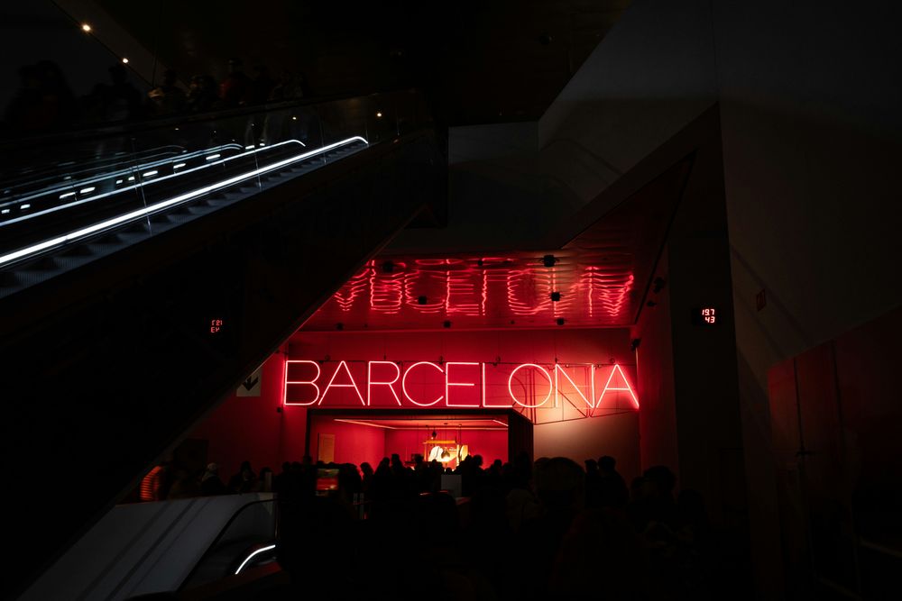 Roter Neon-Schriftzug BARCELONA über Rolltreppen in einem dunklen Innenraum